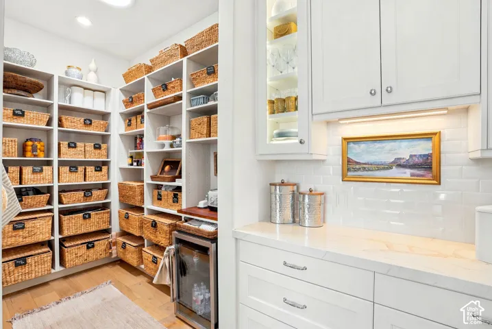Walk-in pantry with extensive built-in shelving, wood-finish flooring, and a beverage cooler