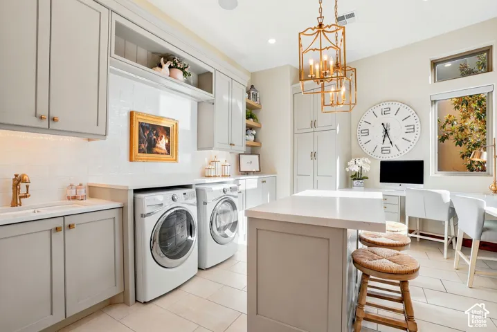 Light-toned cabinetry with brass hardware, integrated washer and dryer units, white subway tile backsplash, white countertop island, and tiled flooring