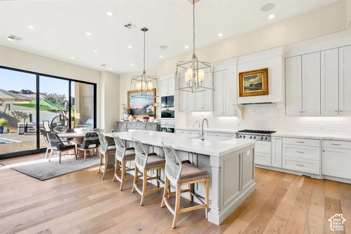 Gourmet kitchen with wood-finish flooring, a large center island, and white shaker cabinetry
