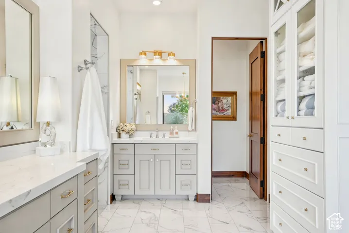 Dual vanity with light gray cabinetry, white countertops, and gold-finish hardware