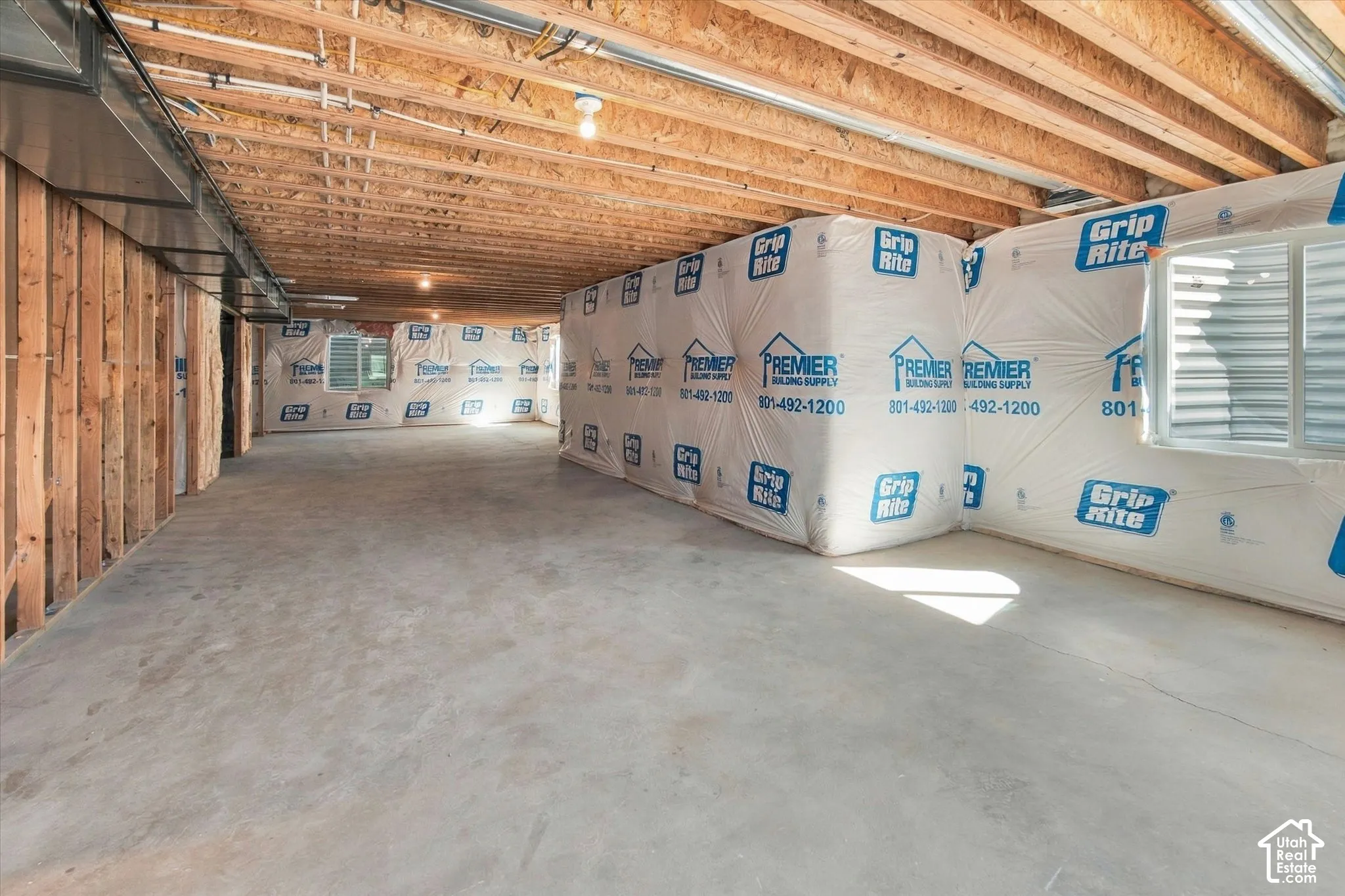 Unfinished basement space with exposed wood framing, concrete flooring, and exposed ceiling joists
