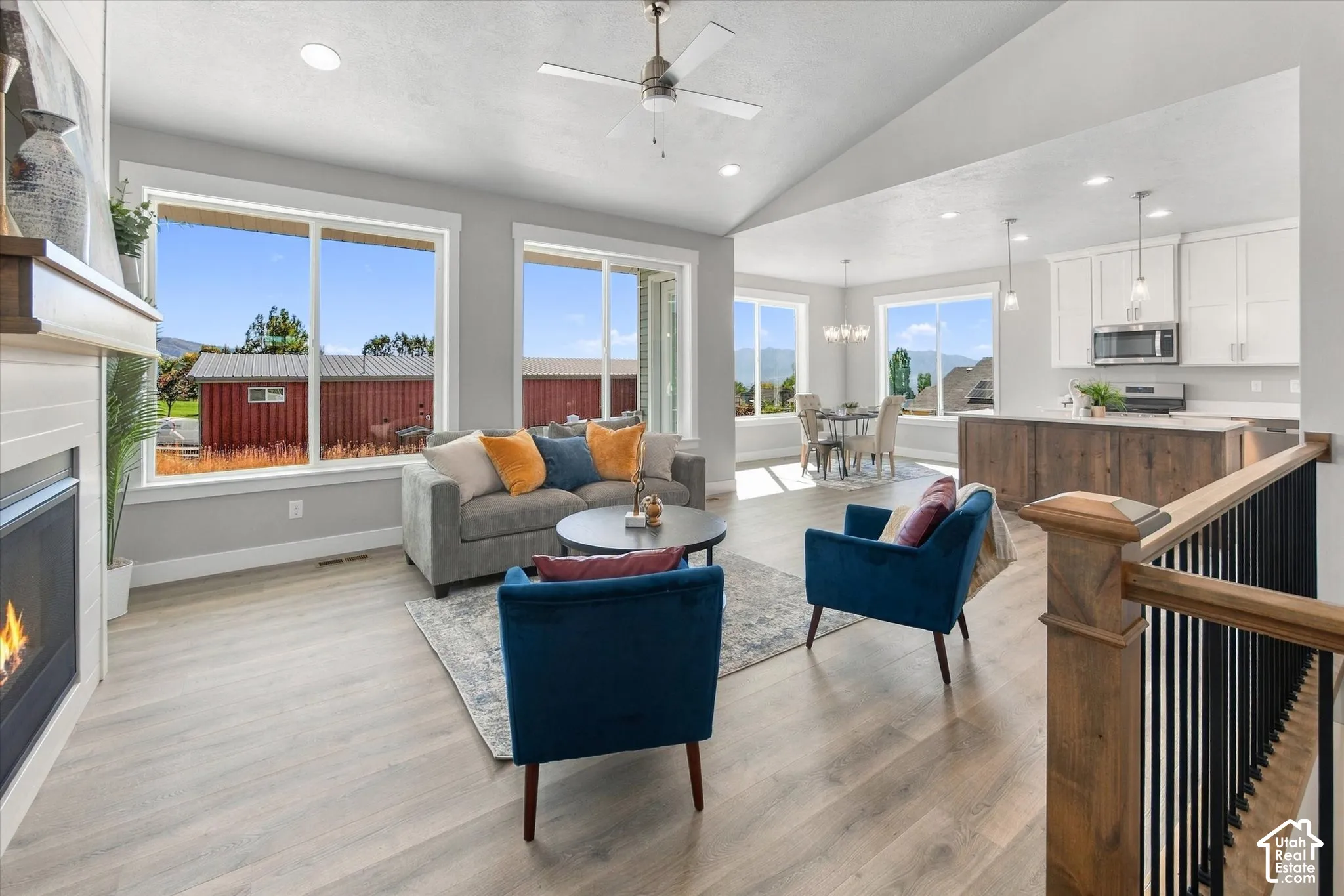 Open-concept living area with vaulted ceilings, wood-finish flooring, a built-in fireplace, and large windows
