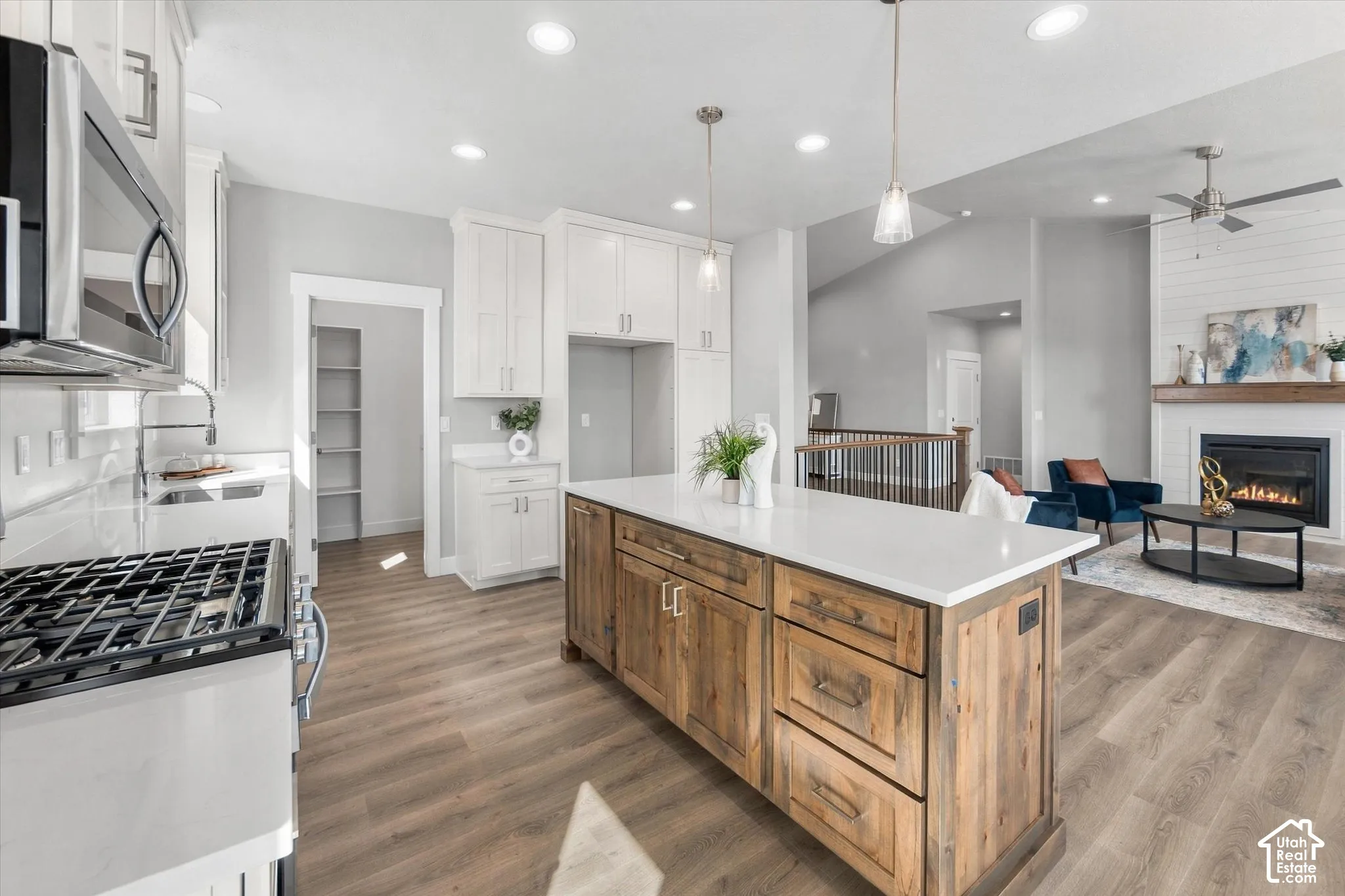 Kitchen featuring white cabinetry, a wood-finish island with a white countertop, stainless steel appliances, and wood-finish flooring