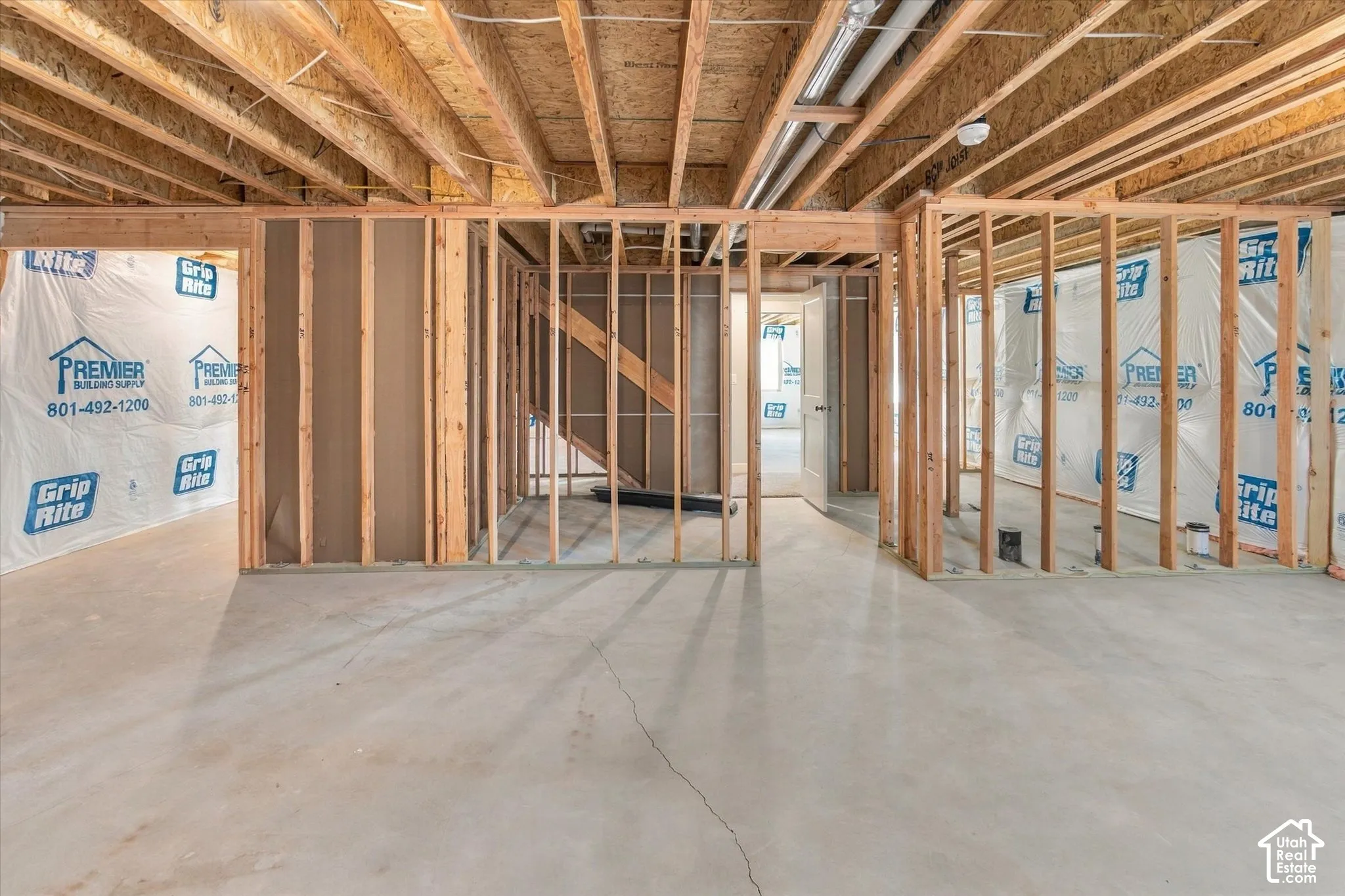 Unfinished lower level featuring exposed wood framing, concrete flooring, and exposed ceiling joists