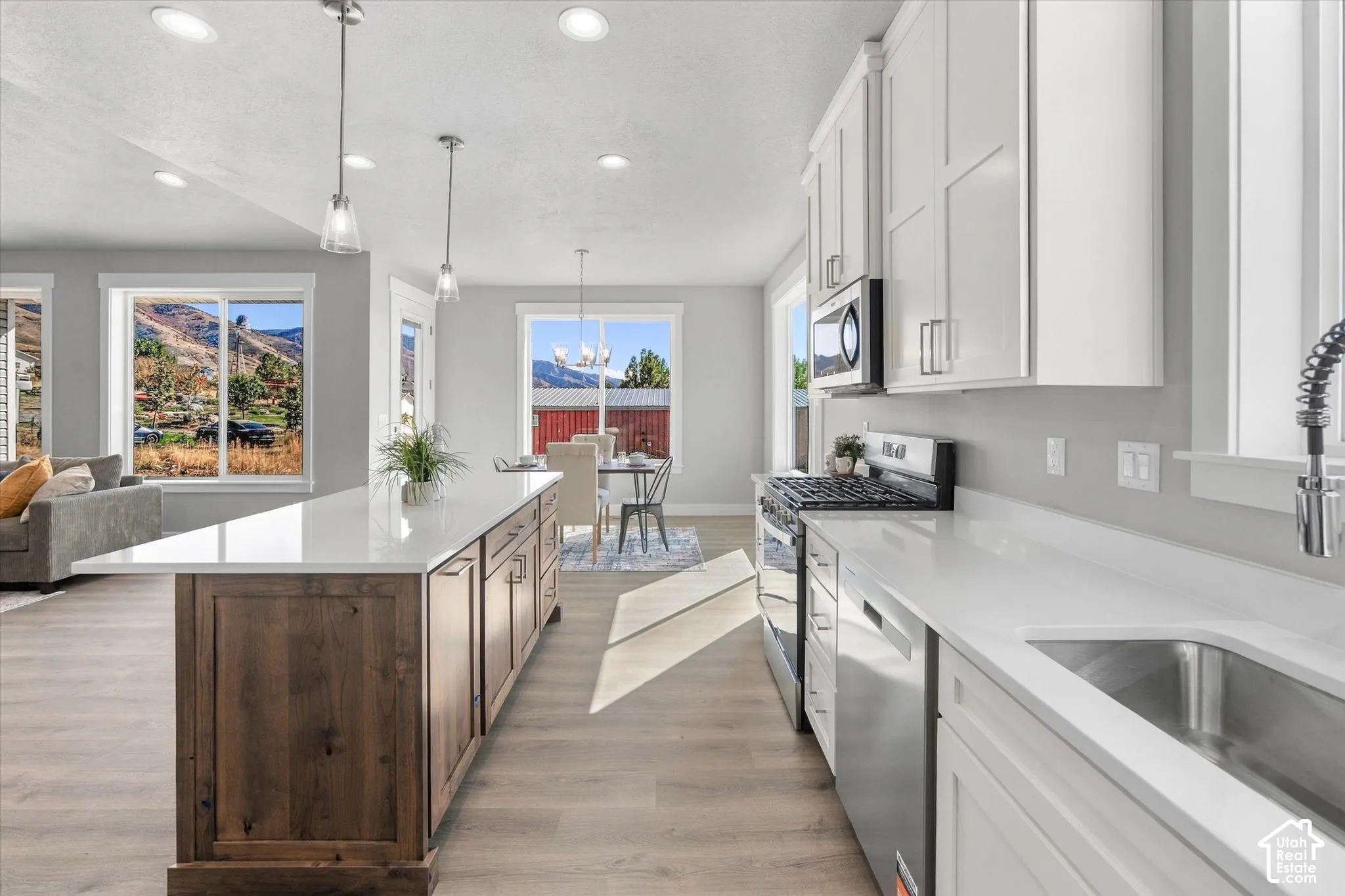 Open-concept kitchen with a wood-finish island, white shaker cabinetry, stainless steel appliances, and light-tone flooring