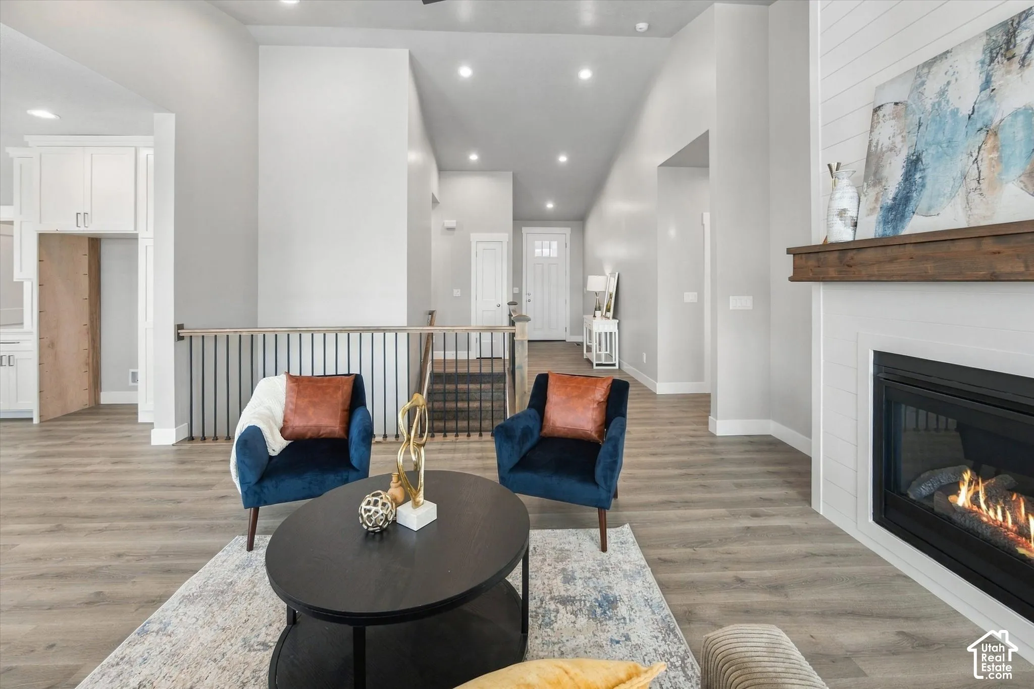 Gas fireplace with a wood mantel, recessed lighting, wood-finish flooring, and a white paneled entry door
