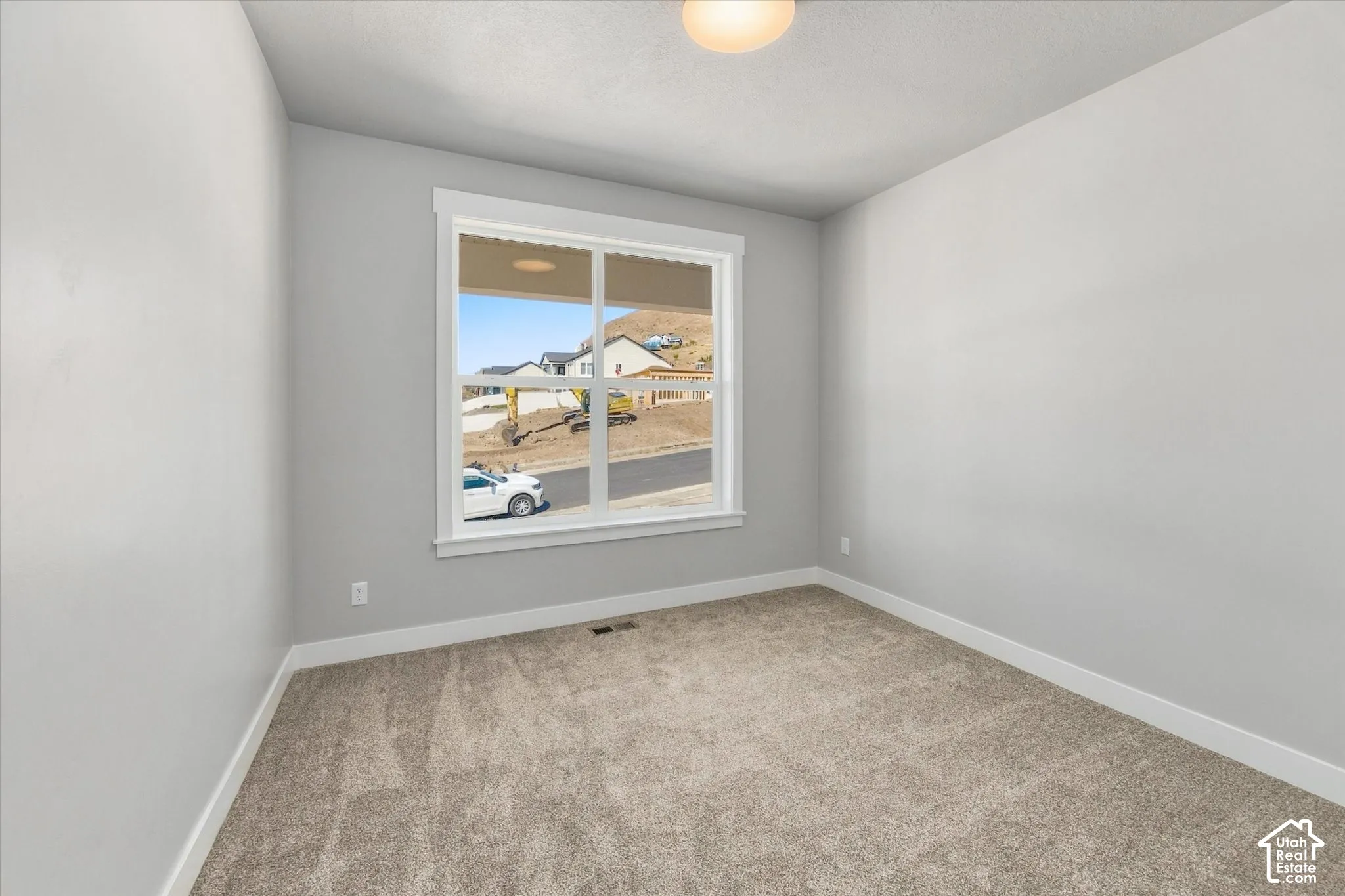 Neutral wall paint, plush carpet flooring, white trim, and a window with white framing