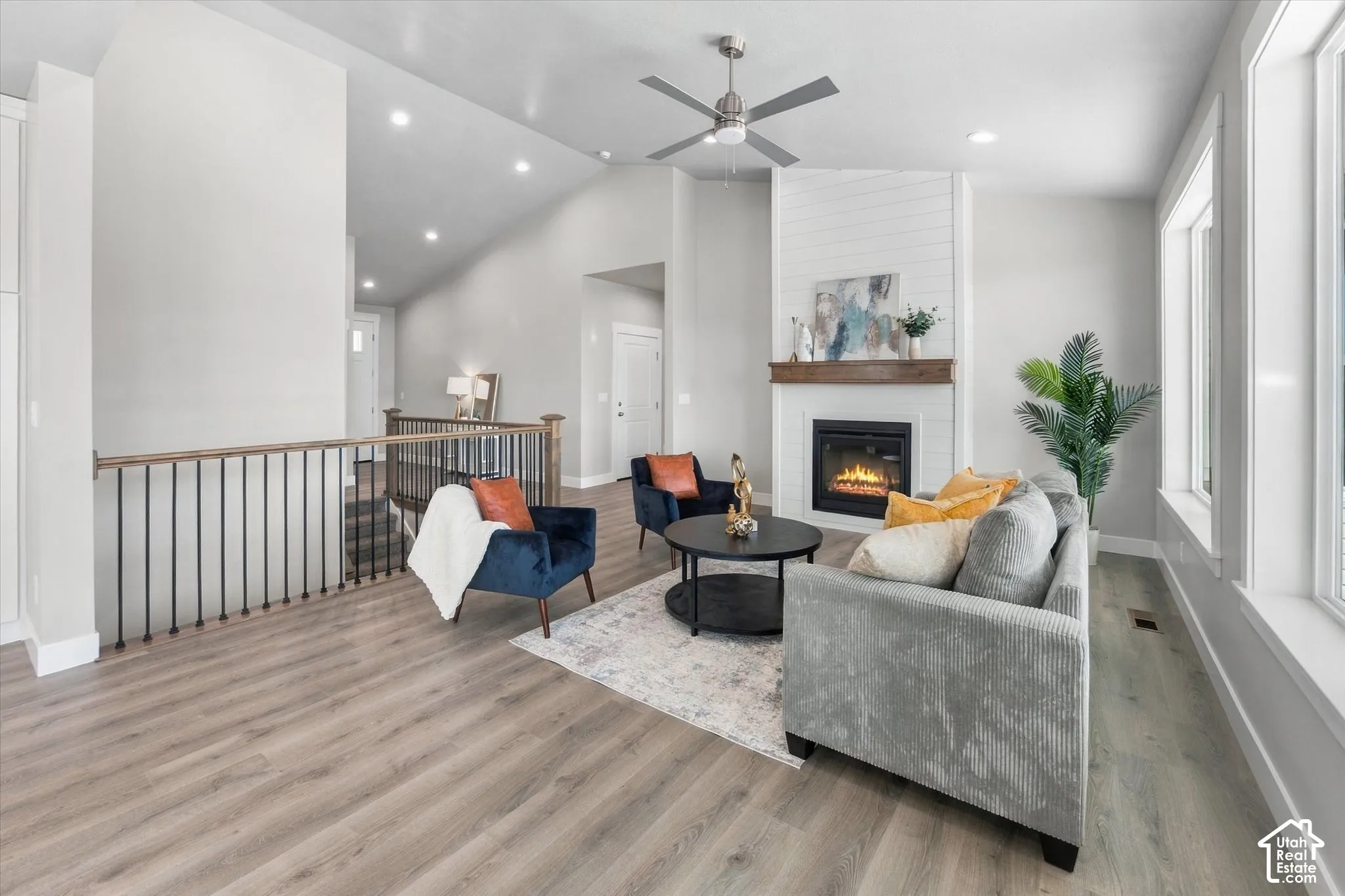 Living space featuring vaulted ceilings, wood-finish flooring, a fireplace with a wood mantle, and an open railing