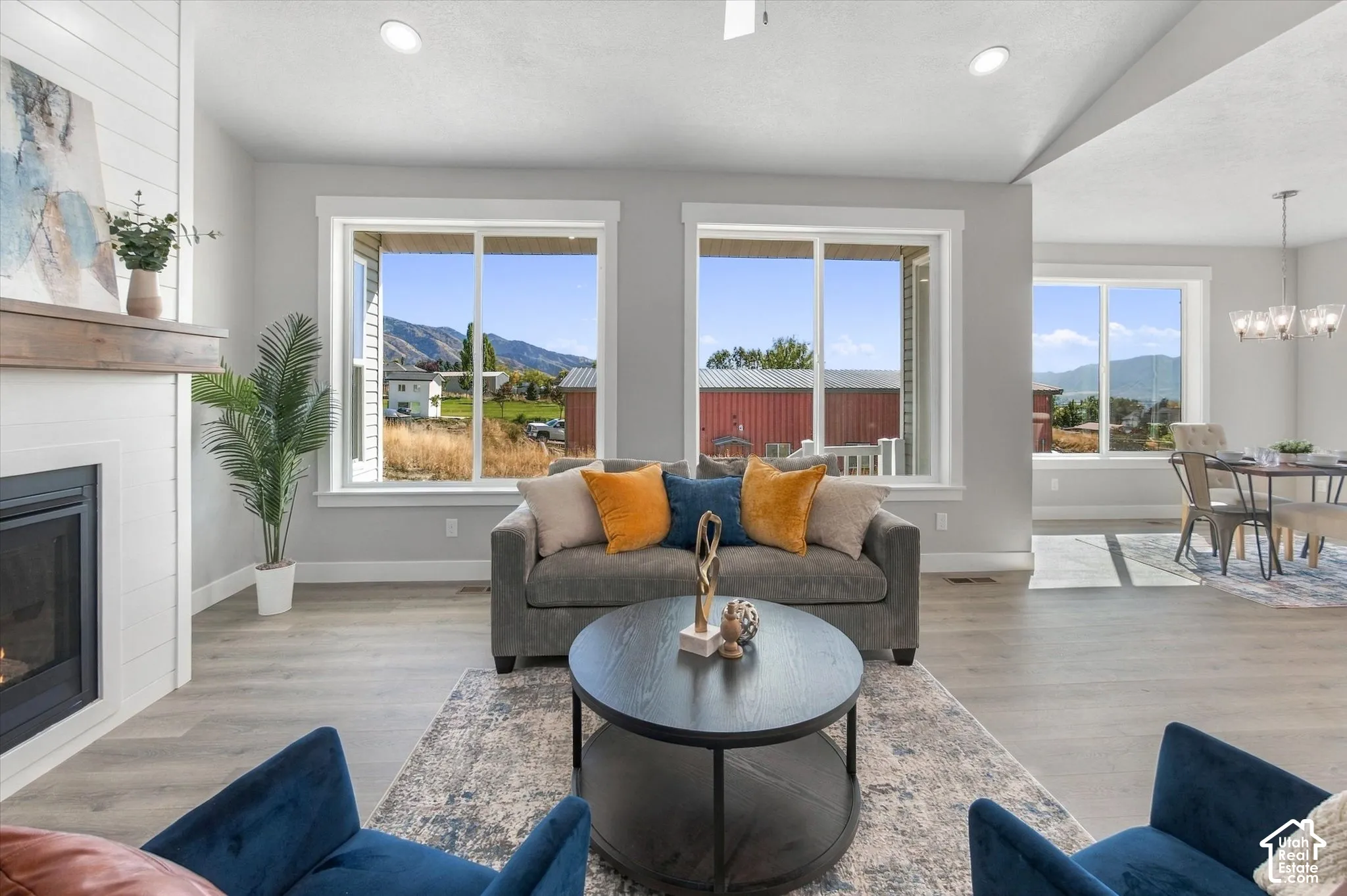 Spacious living area featuring wood-finish flooring, a fireplace with a wood mantle, and white shiplap accent wall