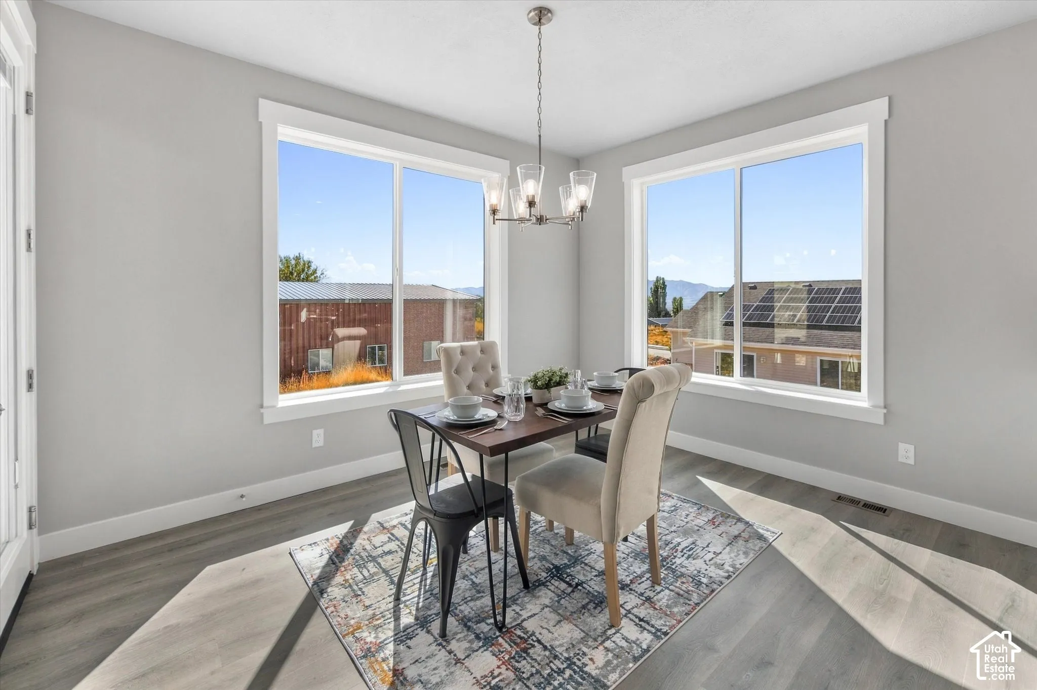 Dining area featuring wood-finish flooring, two large windows, a ceiling-mounted light fixture, and light gray wall paint