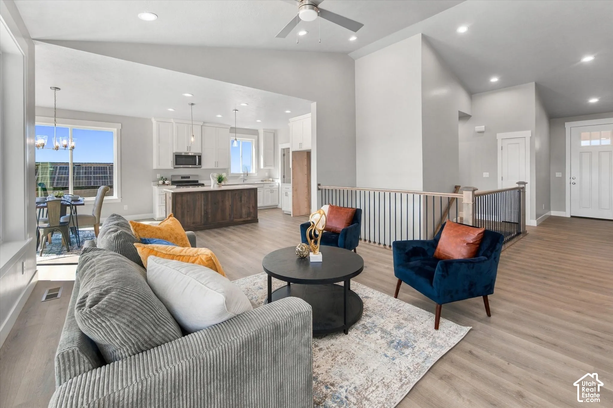 Vaulted ceilings, wood-finish flooring, white cabinetry, recessed lighting, and a modern ceiling fan
