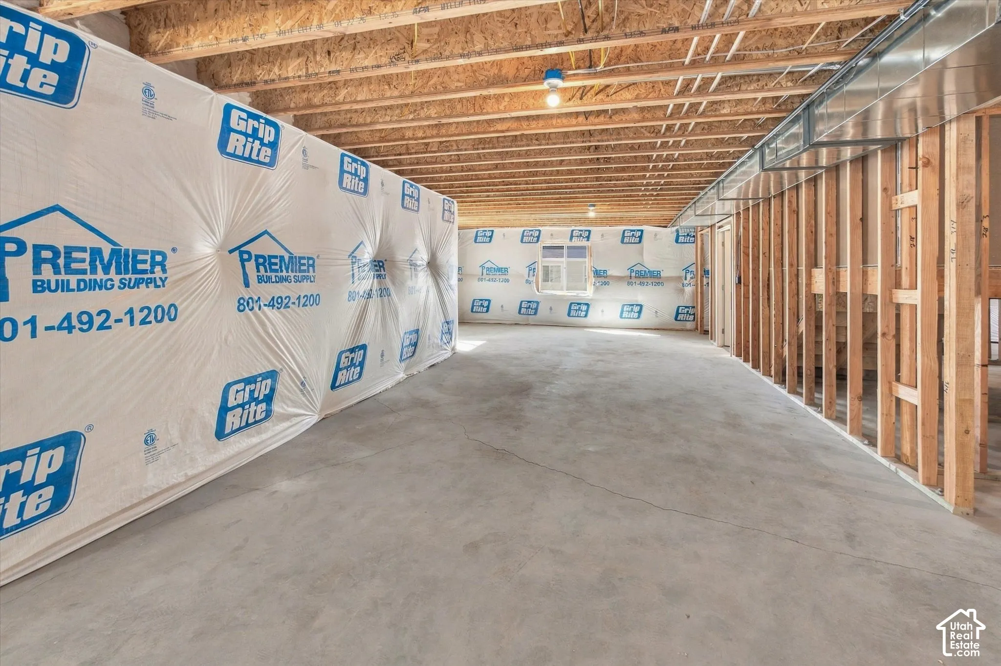 Unfinished basement with concrete flooring, exposed wood framing, and overhead ductwork