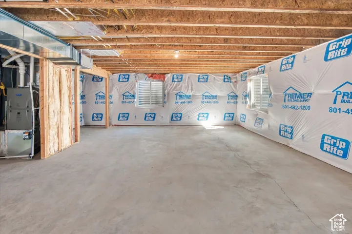 Unfinished basement featuring exposed wood joists, concrete flooring, and visible HVAC ductwork