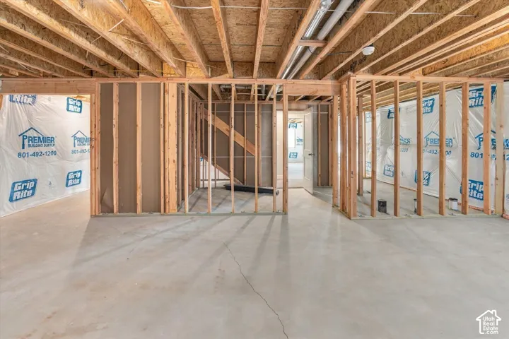 Unfinished lower level featuring exposed wood framing, concrete flooring, and exposed ceiling joists