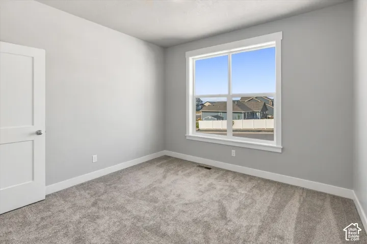 Neutral-toned walls, plush carpeting, and a large window with white trim