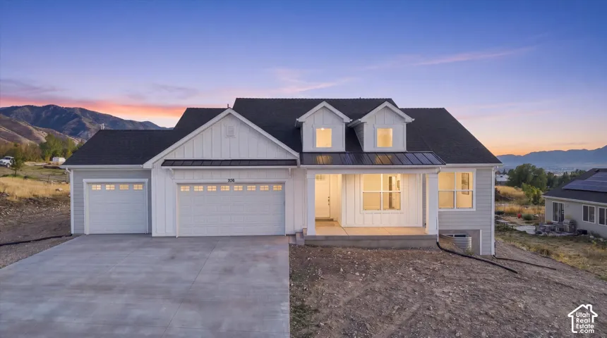 Modern farmhouse architectural style featuring a dark shingle roof, light-toned siding, a covered front porch, and a concrete driveway