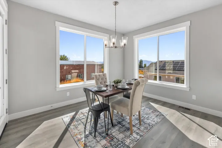 Dining area featuring wood-finish flooring, two large windows, a ceiling-mounted light fixture, and light gray wall paint