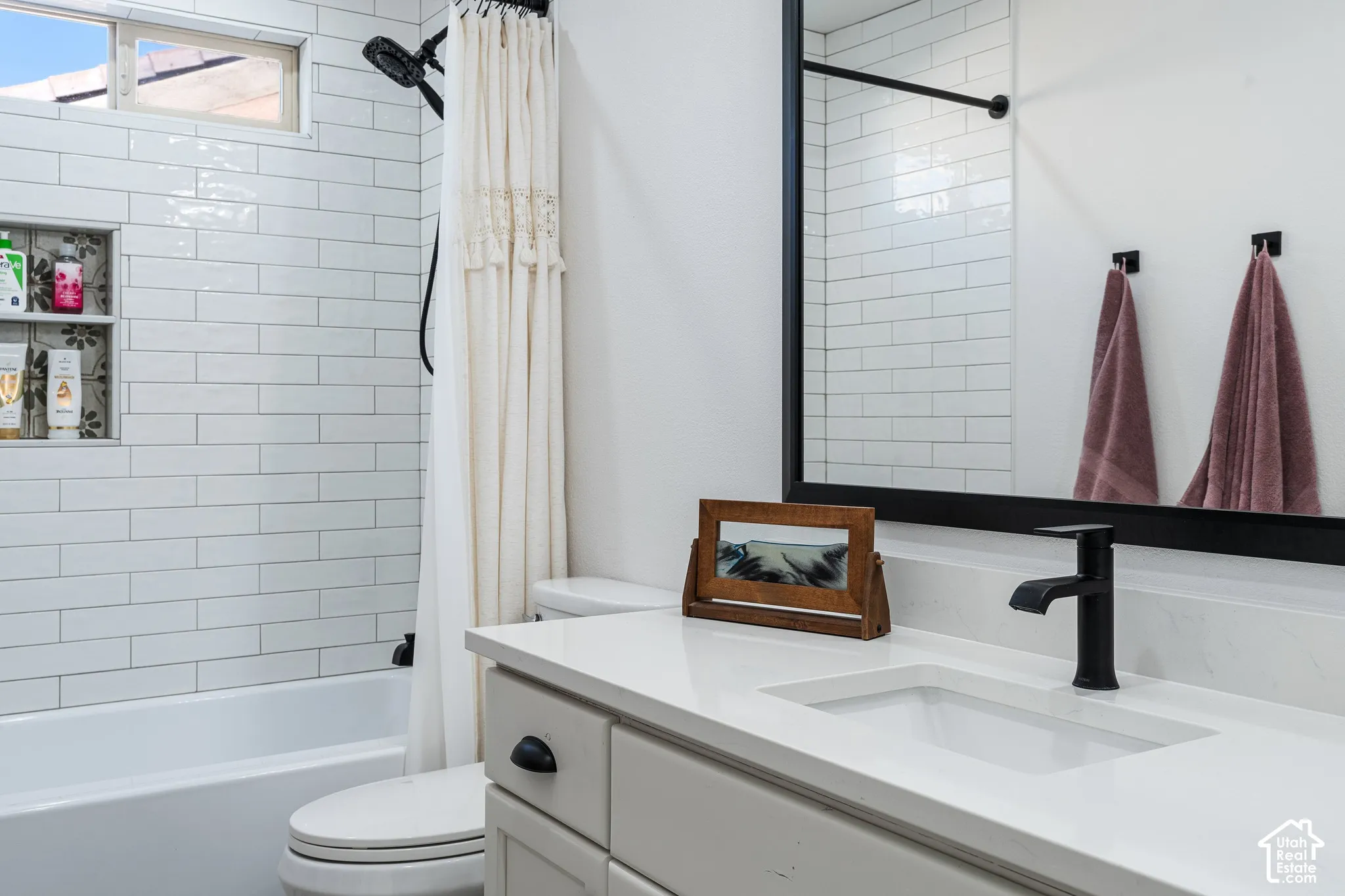 White subway tile shower surround with an integrated niche, a window, and a black showerhead