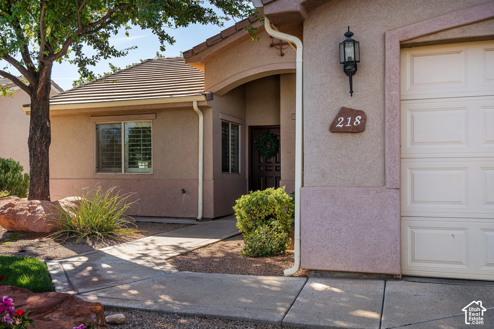 Stucco exterior with an attached garage, covered entryway, and decorative exterior lighting