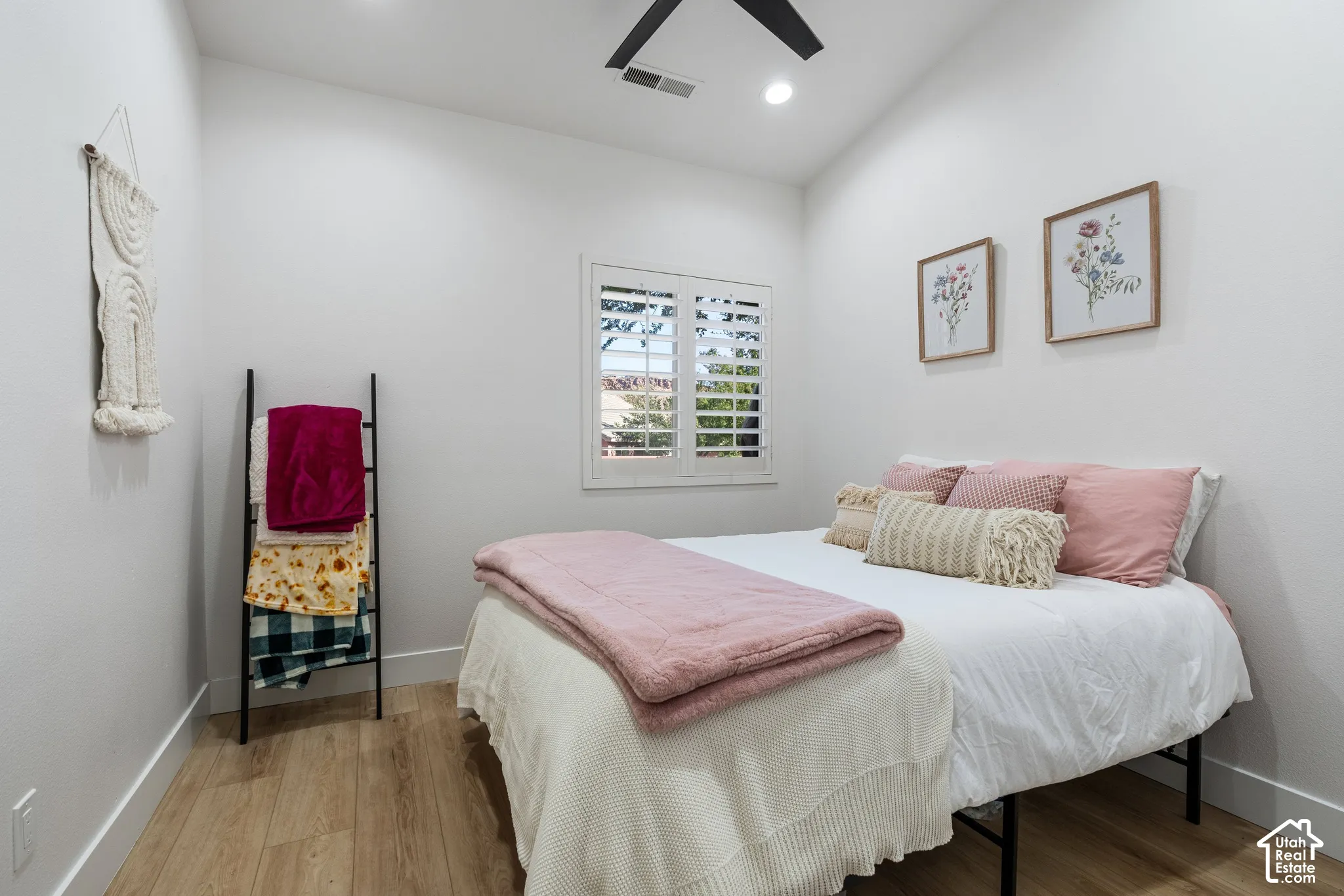 Wood-finish flooring, white walls, and a window with plantation shutters