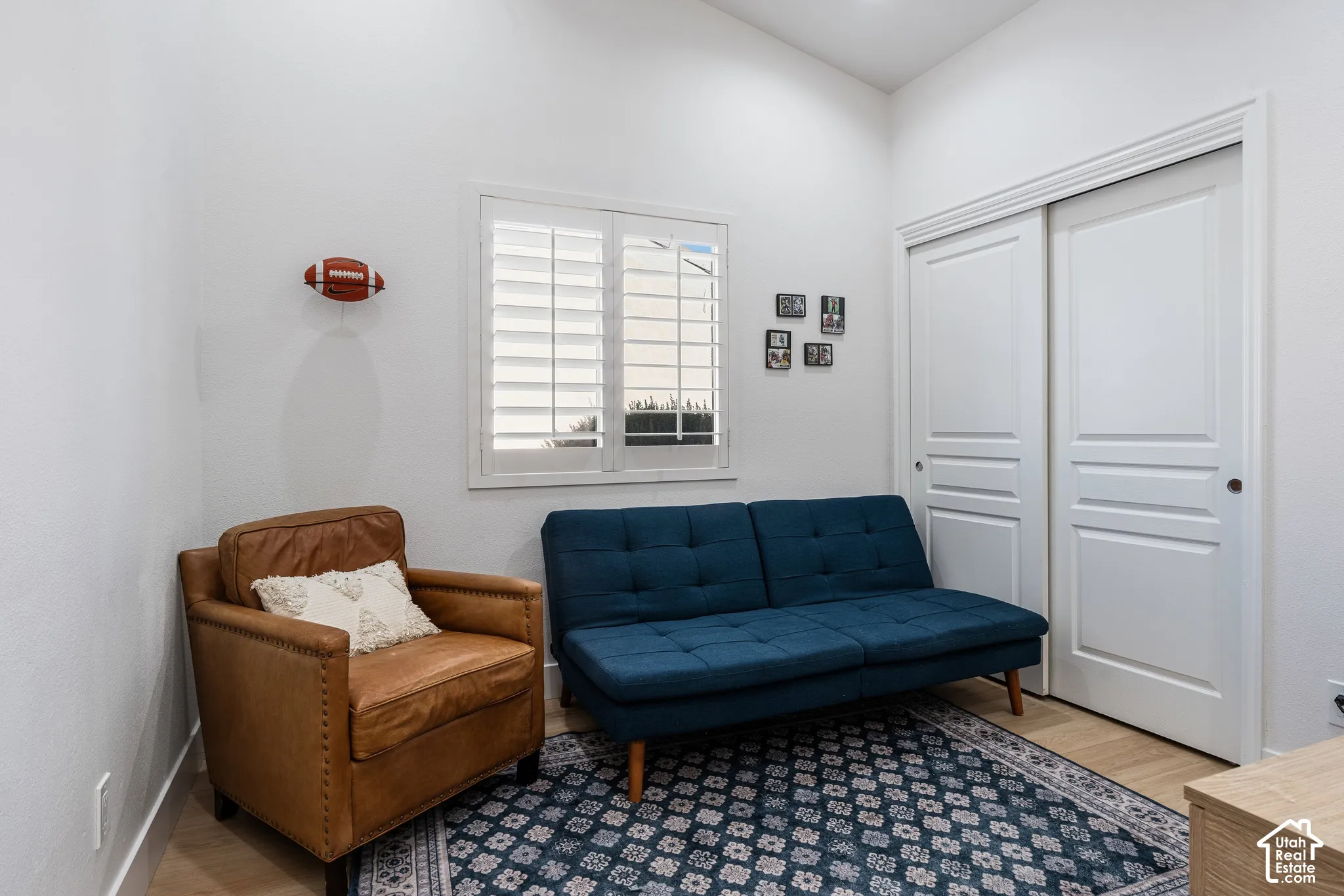 Vaulted ceiling, window with plantation shutters, wood-finish flooring, and a sliding closet door