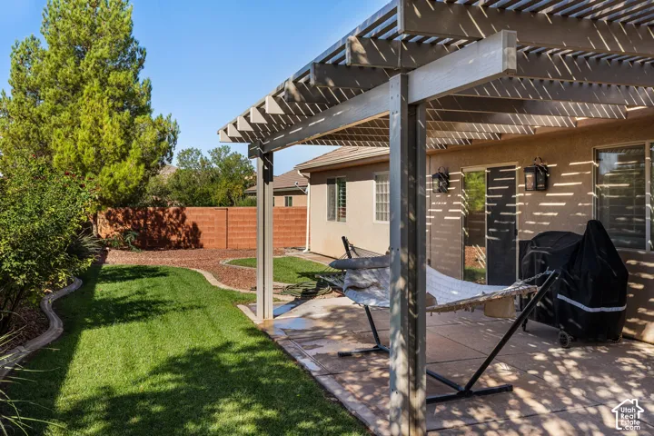 Backyard featuring a slatted pergola, concrete patio, and a manicured lawn