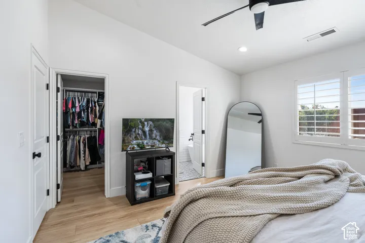 White walls, wood-finish flooring, ceiling fan, recessed lighting, and window with plantation shutters