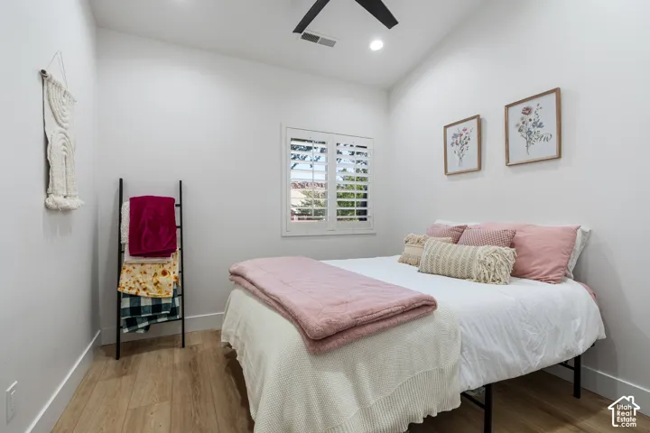 Wood-finish flooring, white walls, and a window with plantation shutters