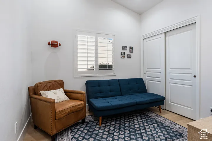 Vaulted ceiling, window with plantation shutters, wood-finish flooring, and a sliding closet door