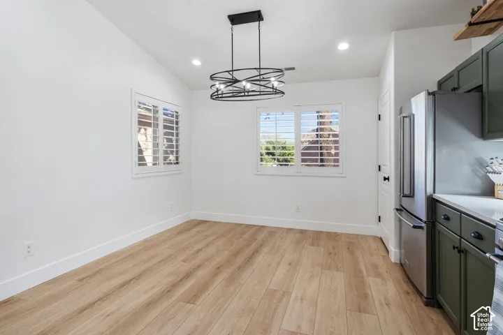 Wood-finish flooring, vaulted ceiling, recessed lighting, plantation shutters, and a contemporary chandelier