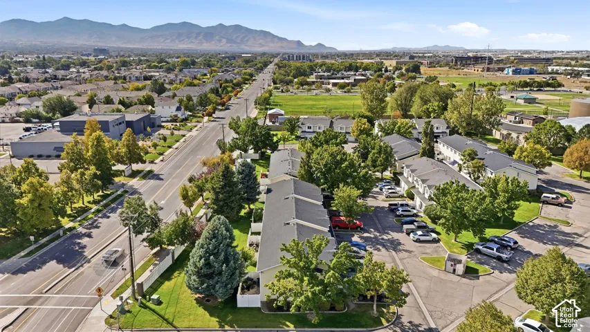 Aerial perspective featuring multi-building property, mature trees, paved parking areas, and adjacent roadways