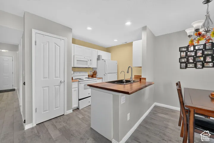 Kitchen featuring white cabinetry, white appliances, wood-finish countertops, and recessed lighting