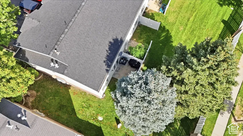 Asphalt shingle roof, mature landscaping, manicured lawn, paved patio, and perimeter fencing