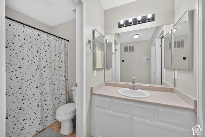 White vanity with panel-front cabinetry, single basin sink, and a light-toned countertop