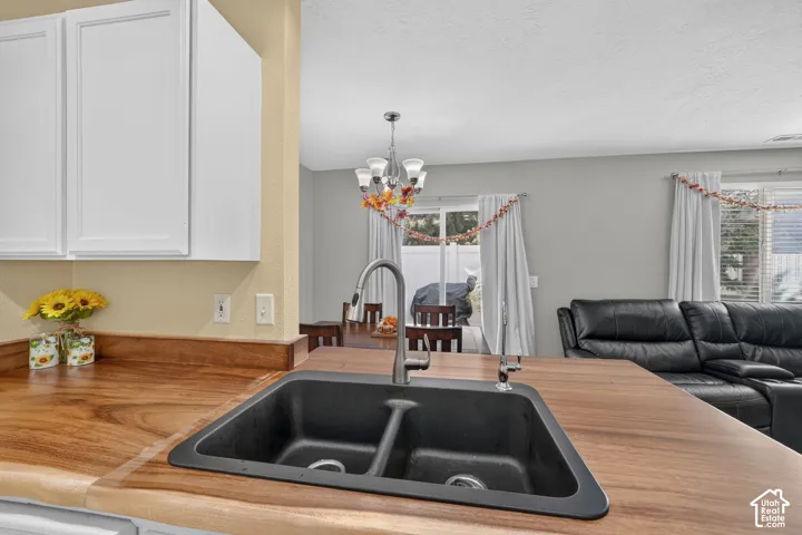 Wood-finish countertops, white upper cabinetry, and a black double-basin sink with a gooseneck faucet