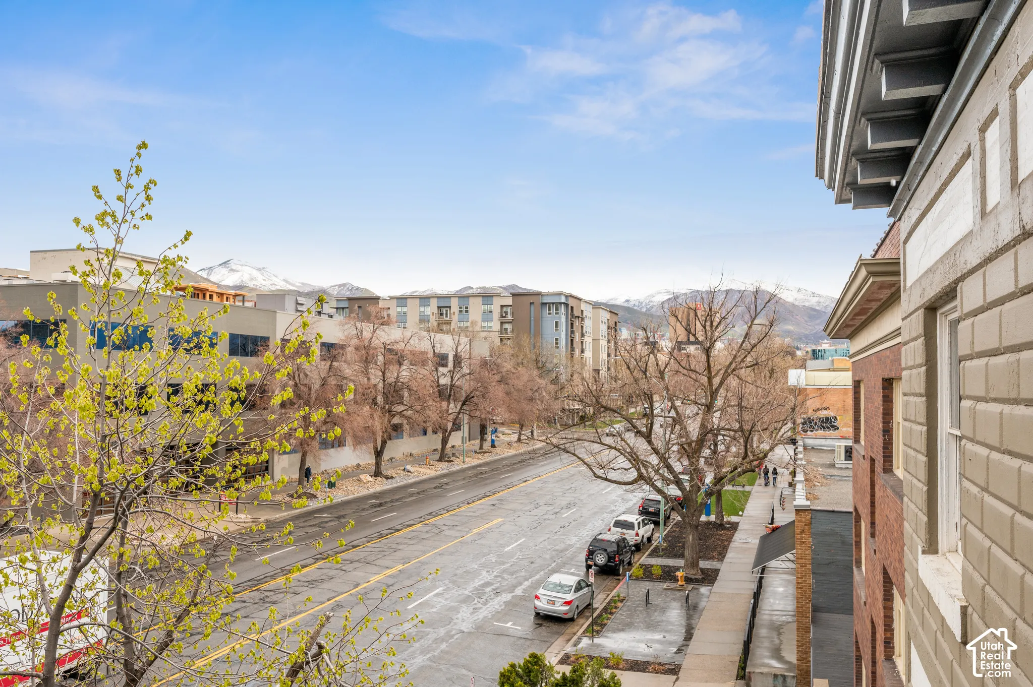 Cityscape with a prominent street, surrounding buildings, and distant snow-capped mountains