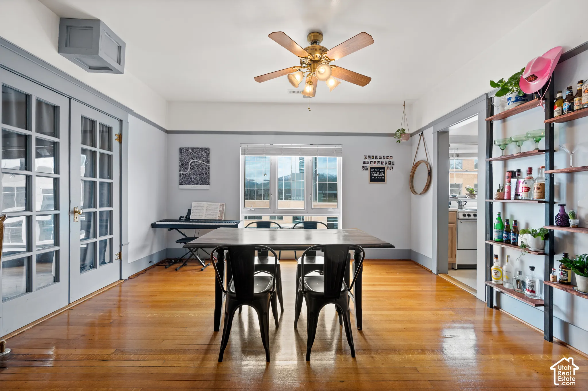 Hardwood flooring throughout, French doors with glass panes, ceiling fan with integrated lighting, and built-in shelving
