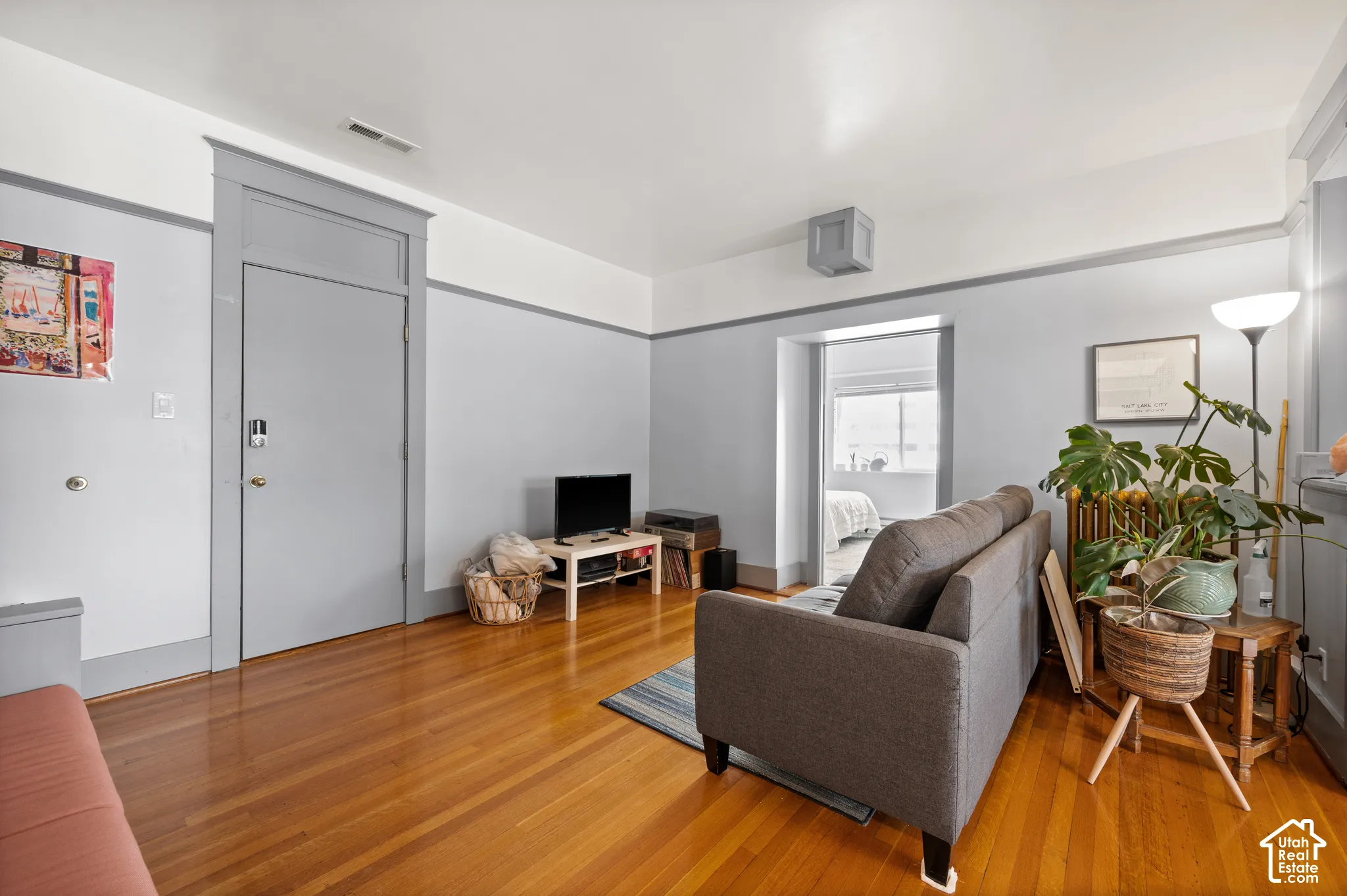 Hardwood flooring, painted interior door with trim, light blue wall paint with white trim, and a recessed doorway