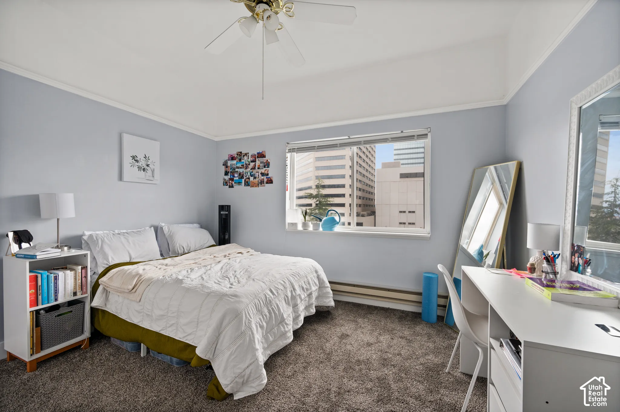 Carpeted flooring, a window offering city architecture, and a ceiling fan with integrated lighting