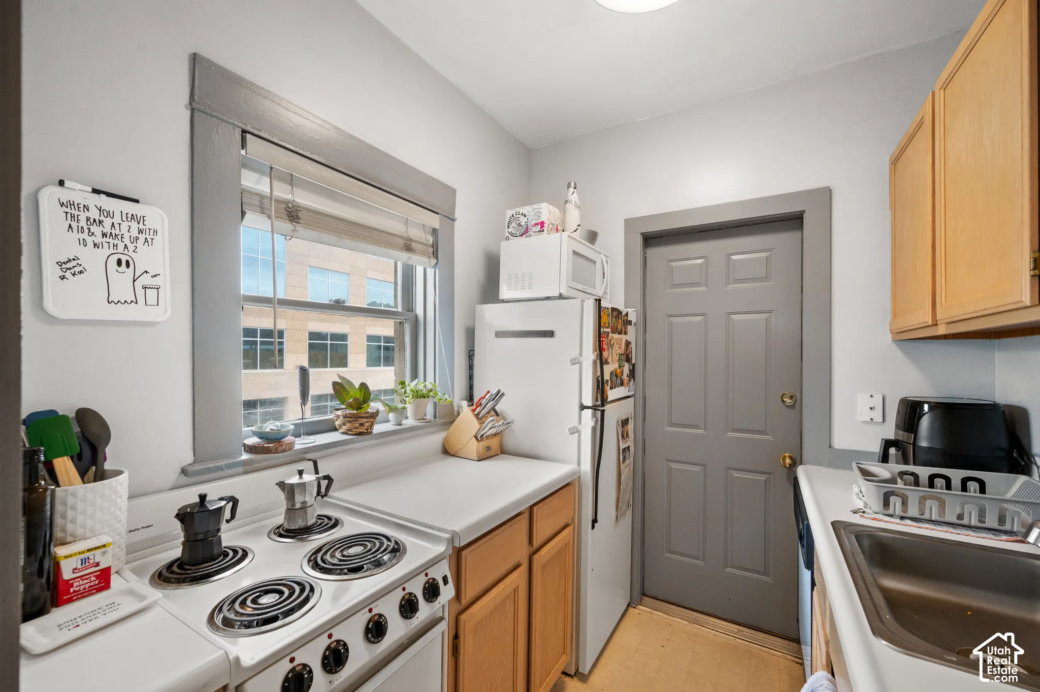 Kitchen featuring wood-finish cabinetry, white countertops, a four-burner electric range, and a stainless steel sink