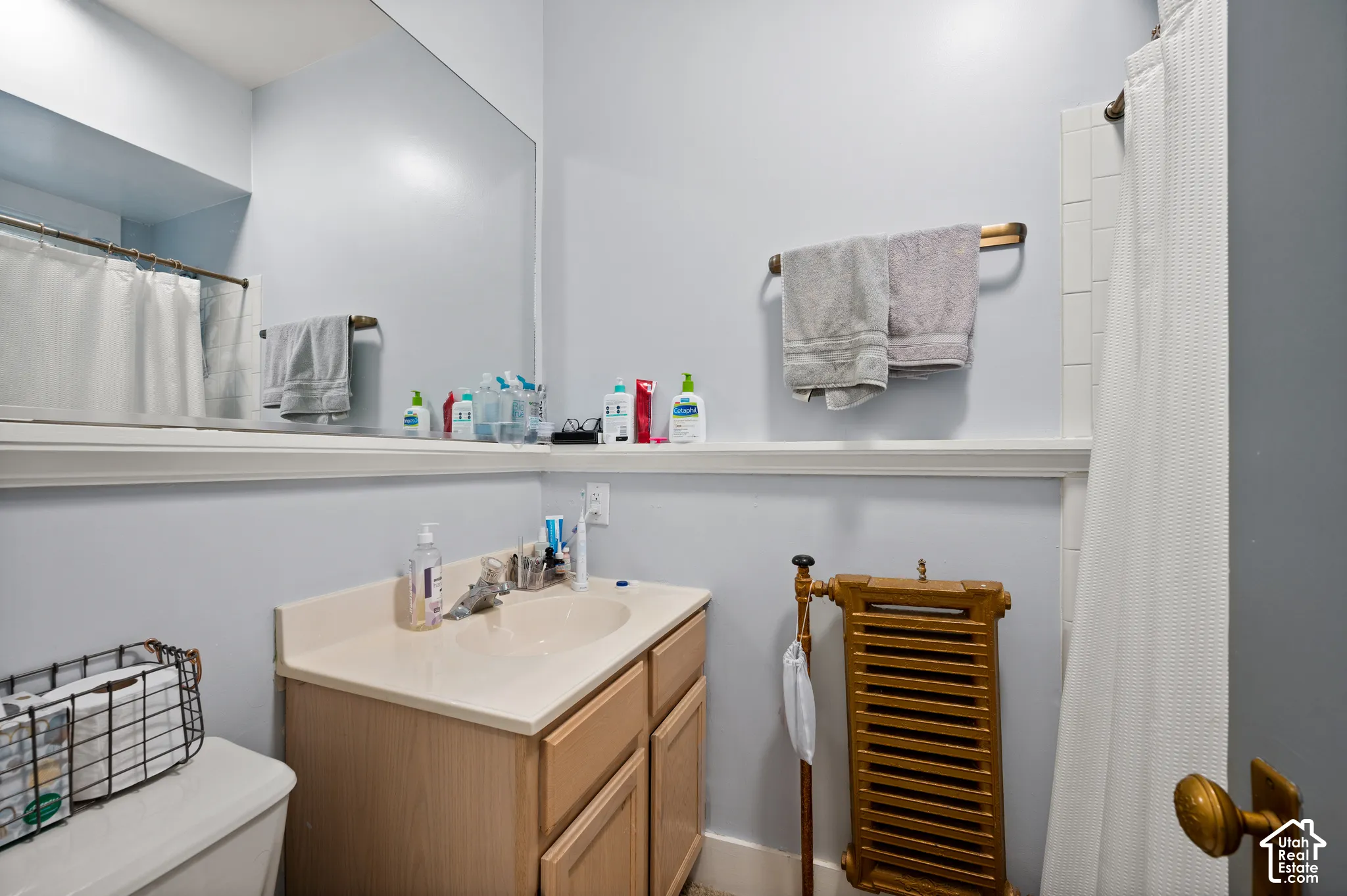 Vanity with integrated sink, wood-finish cabinetry, and full-wall mirror