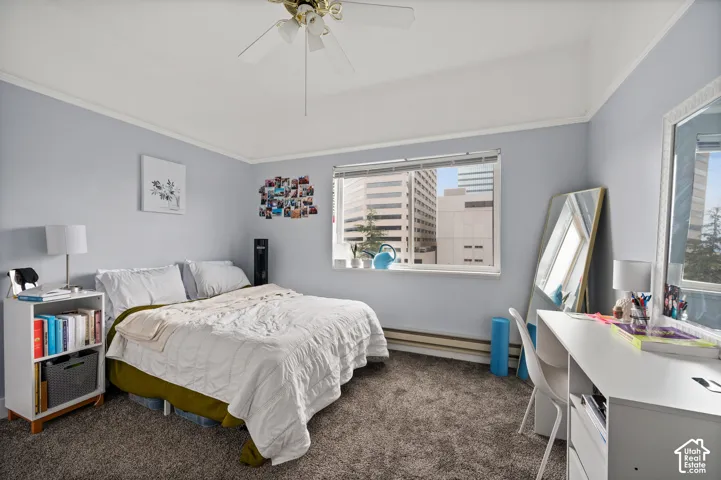 Carpeted flooring, a window offering city architecture, and a ceiling fan with integrated lighting