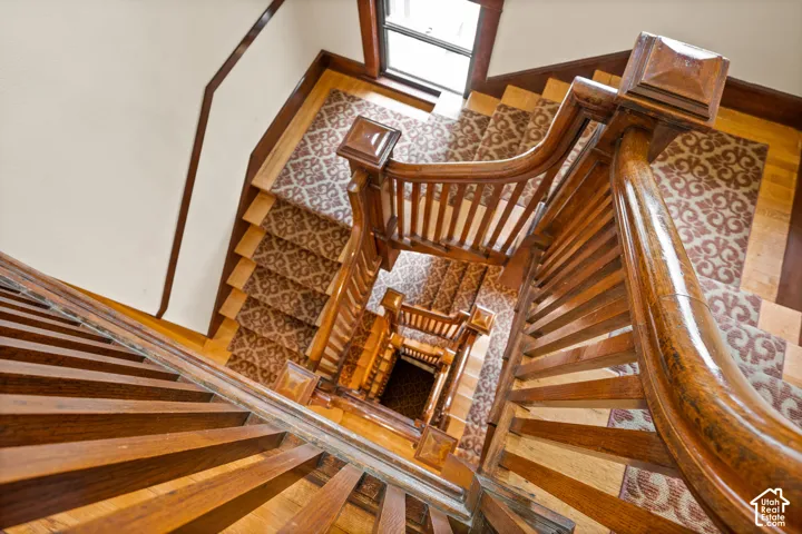 Staircase featuring wood steps, ornate wood banisters, and patterned stair runner