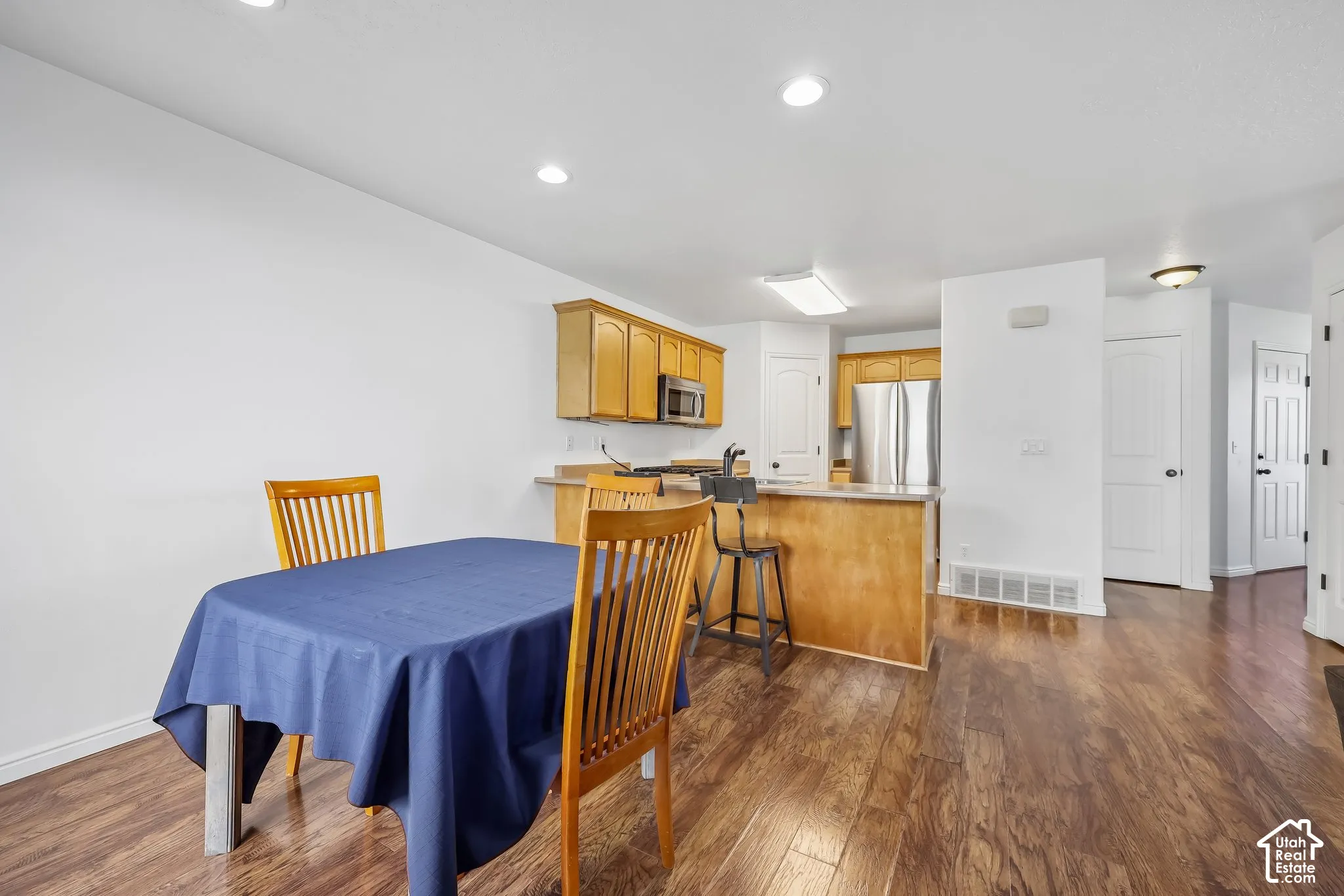 Open-concept kitchen featuring wood-finish flooring, light wood cabinetry, recessed lighting, and stainless steel appliances