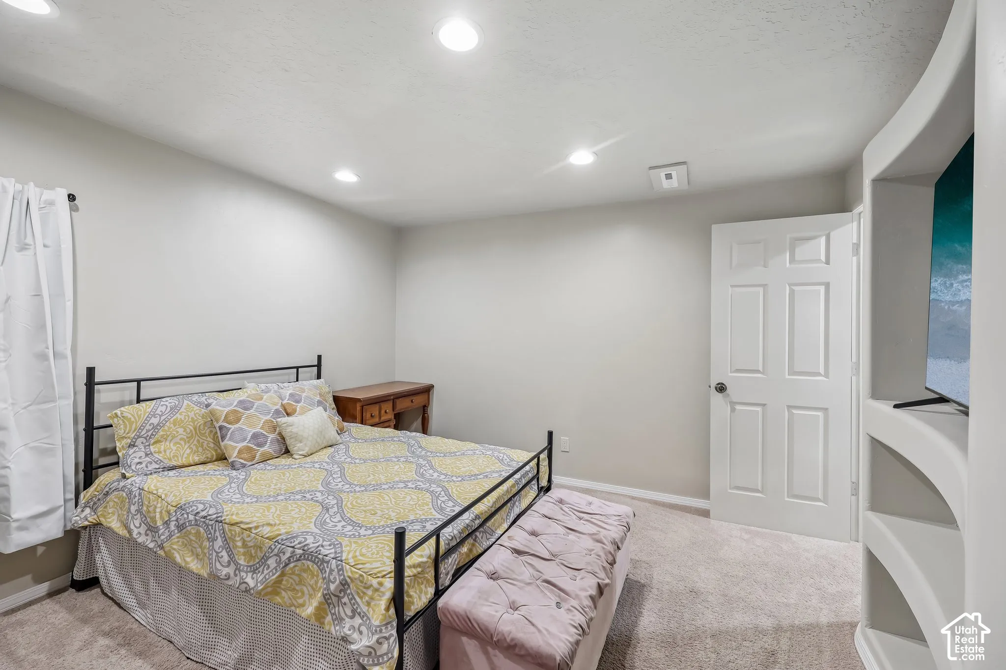 Recessed ceiling lighting, light-toned wall paint, neutral carpet flooring, and a built-in shelving unit