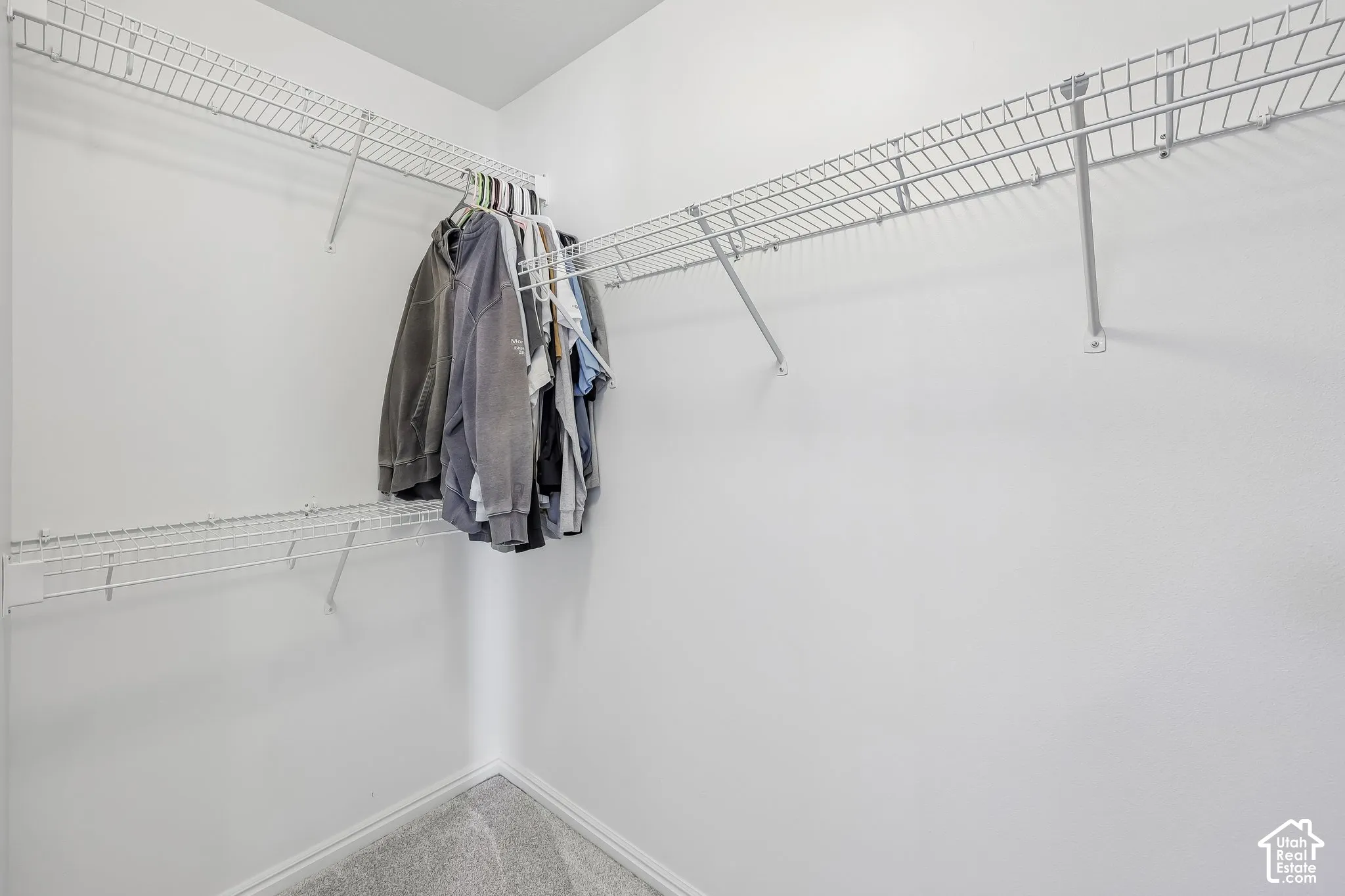 Wall-mounted wire shelving system with hanging rods in a white-walled interior