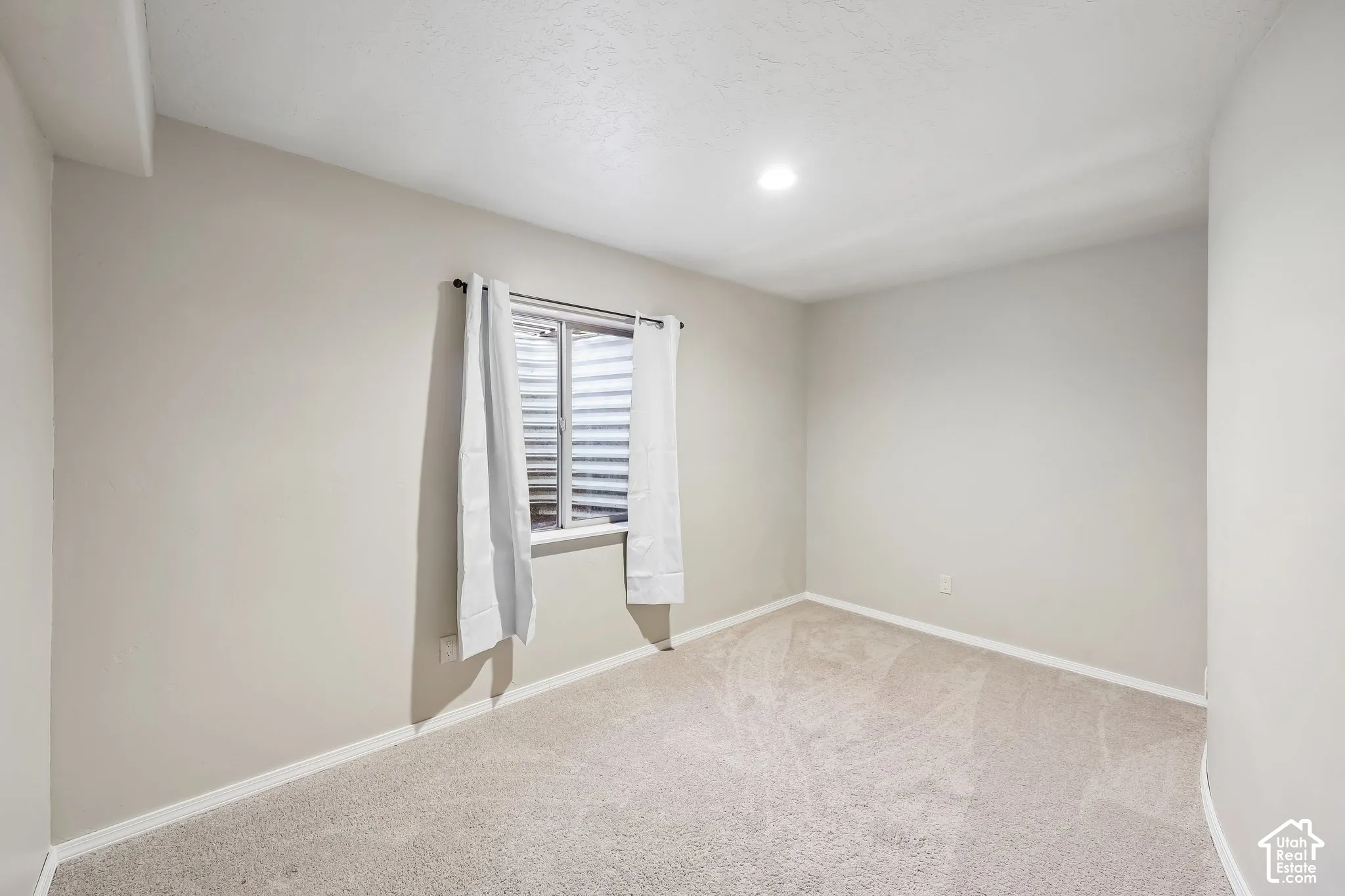 Recessed lighting, light-toned carpeting, neutral wall paint, and white trim molding