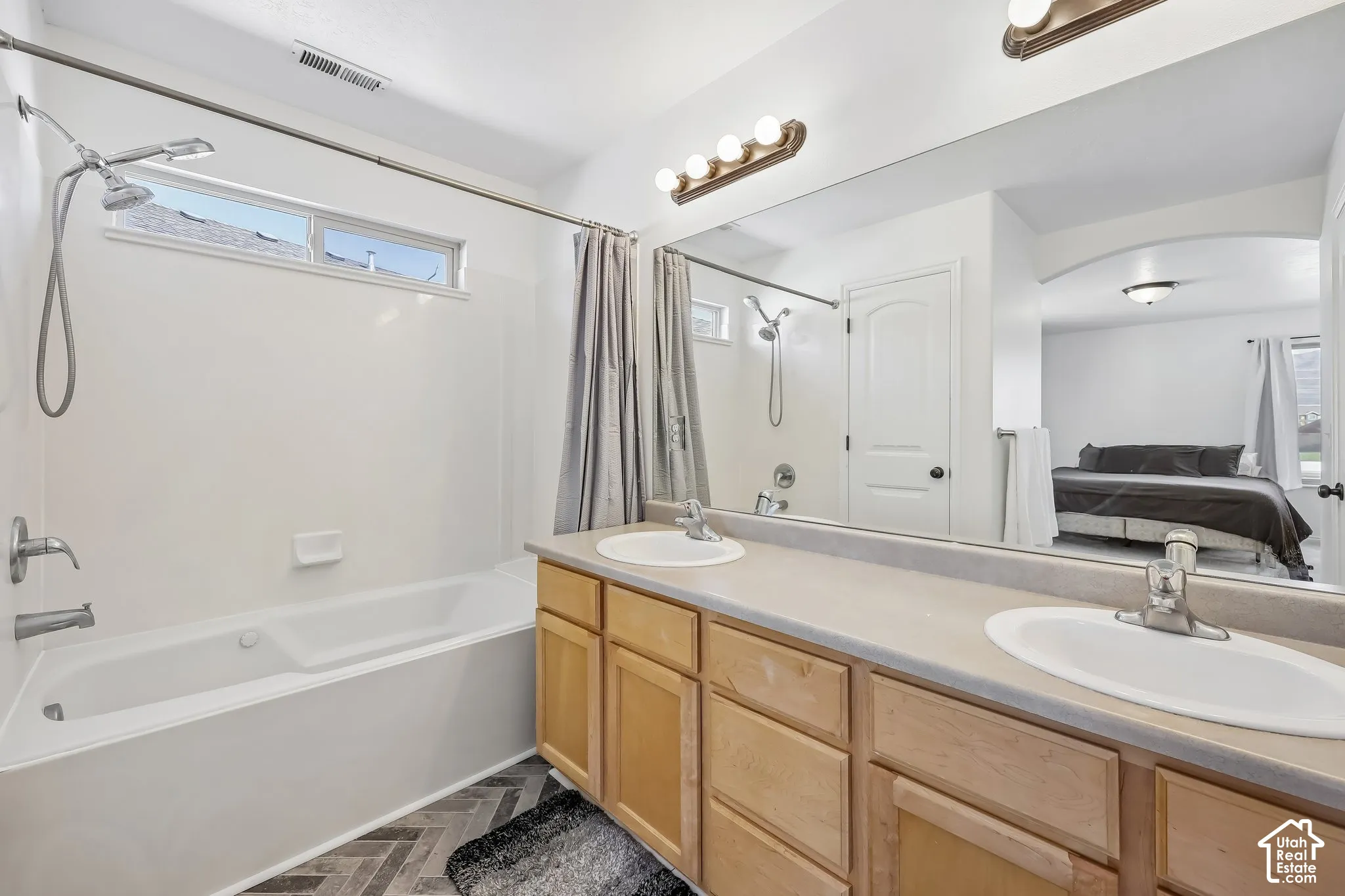 Double vanity with integrated sinks, light wood-finish cabinetry, and a large wall-mounted mirror