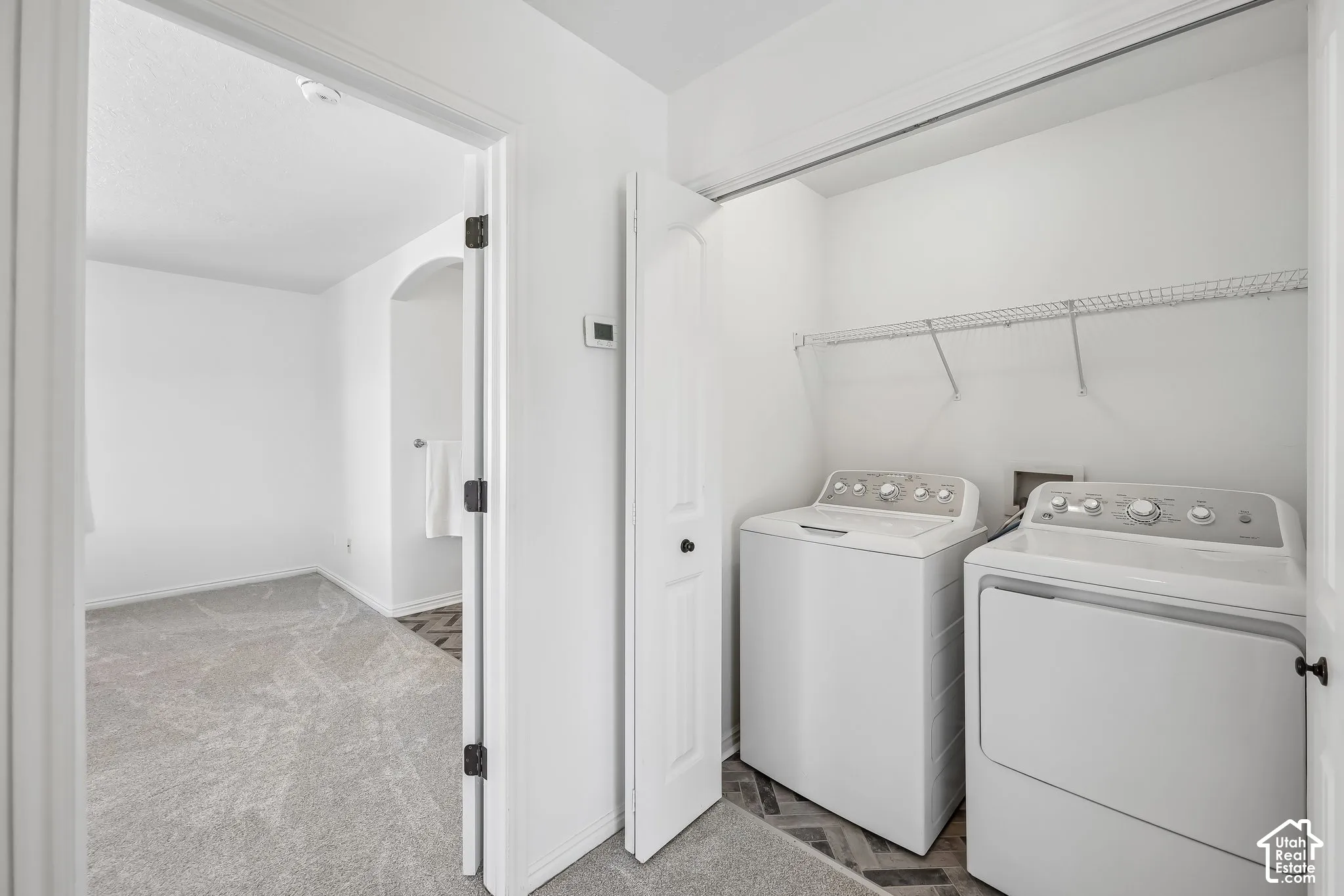 Dedicated laundry area with wire shelving, herringbone-patterned flooring, and a nearby arched entryway