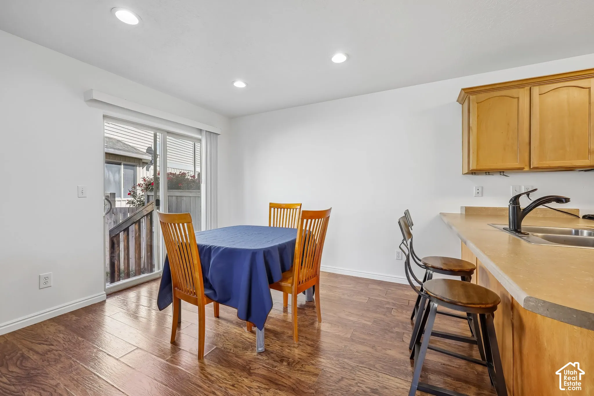 Recessed ceiling lighting, wood-finish flooring, sliding glass door, and a kitchen counter with an integrated sink
